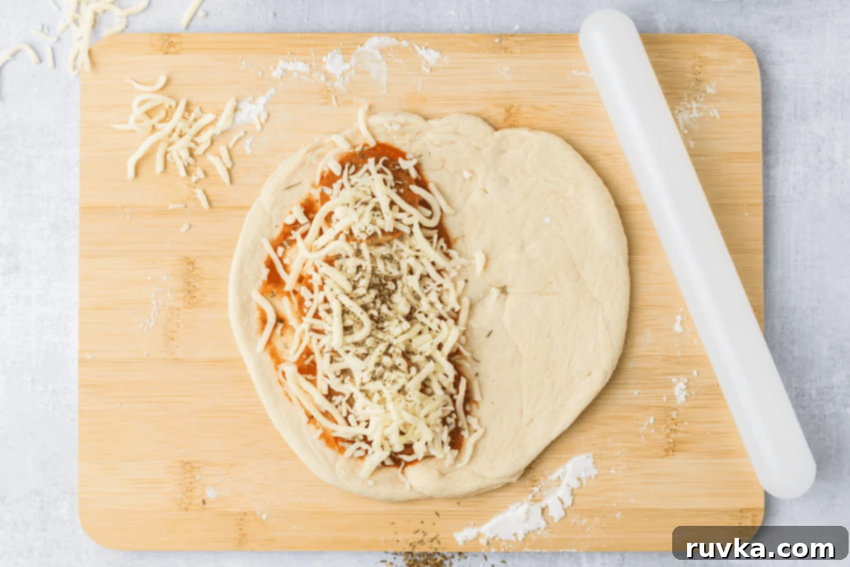 Air-Fried Calzone Pockets 5 Dough rolled into a circle, then topped with sauce, cheese, pepperoini, and seasoning. On a cutting board.
