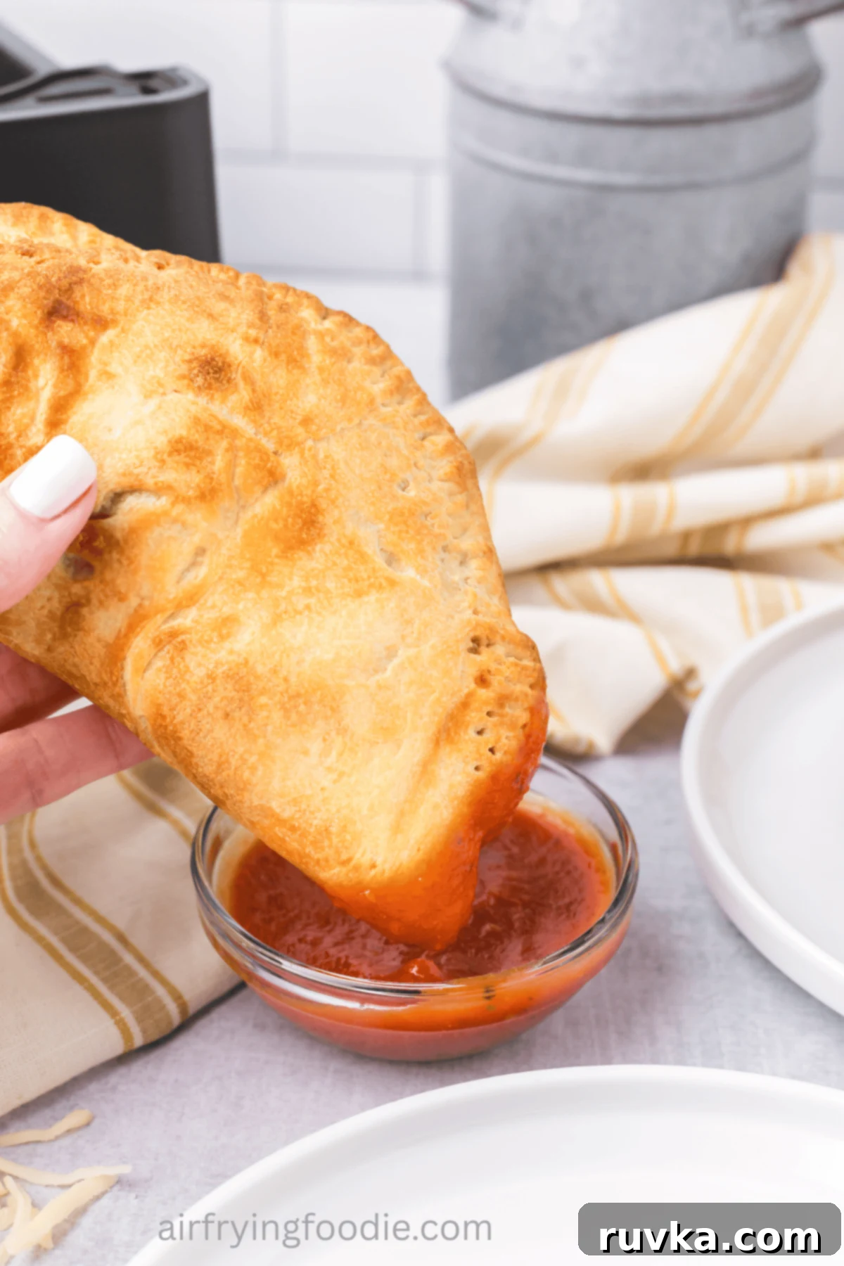 Air-Fried Calzone Pockets 9 Calzone being dipped into pizza sauce.