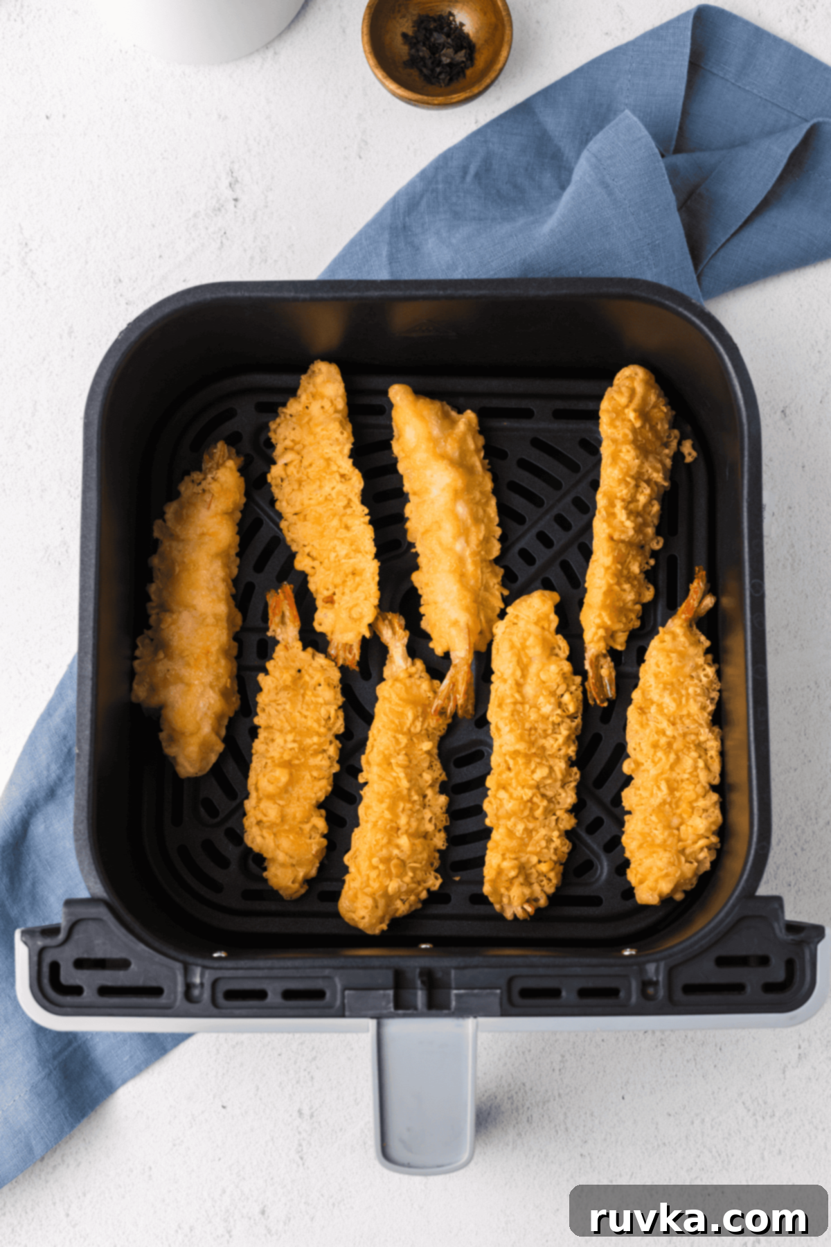Crispy Air Fryer Frozen Shrimp Tempura 4 Frozen shrimp tempura pieces arranged in a single layer in an air fryer basket, ready for cooking.