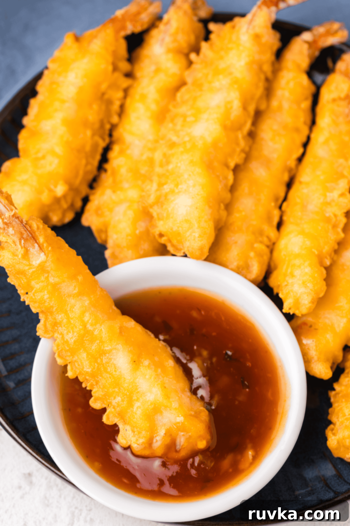 Crispy Air Fryer Frozen Shrimp Tempura 6 Close-up of crispy shrimp tempura dipped in a flavorful sauce, ready to eat.