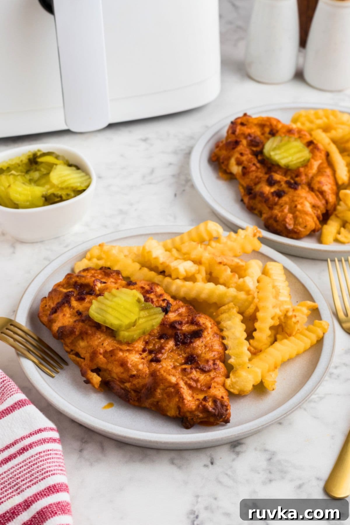 Crispy Air Fryer Nashville Hot Chicken 2 Air fryer Nashville Hot Chicken on a white plate with French fries as a side.