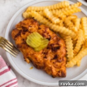 Crispy Air Fryer Nashville Hot Chicken 11 Air fryer Nashville Hot Chicken on a white plate with French fries as a side.