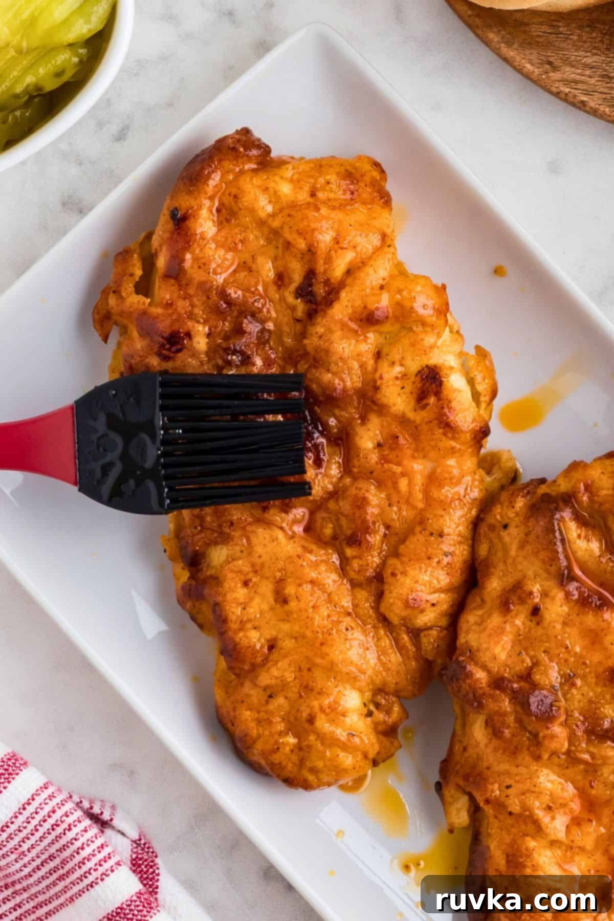Crispy Air Fryer Nashville Hot Chicken 8 Sauce being brushed onto pieces of chicken after being cooked in the air fryer.
