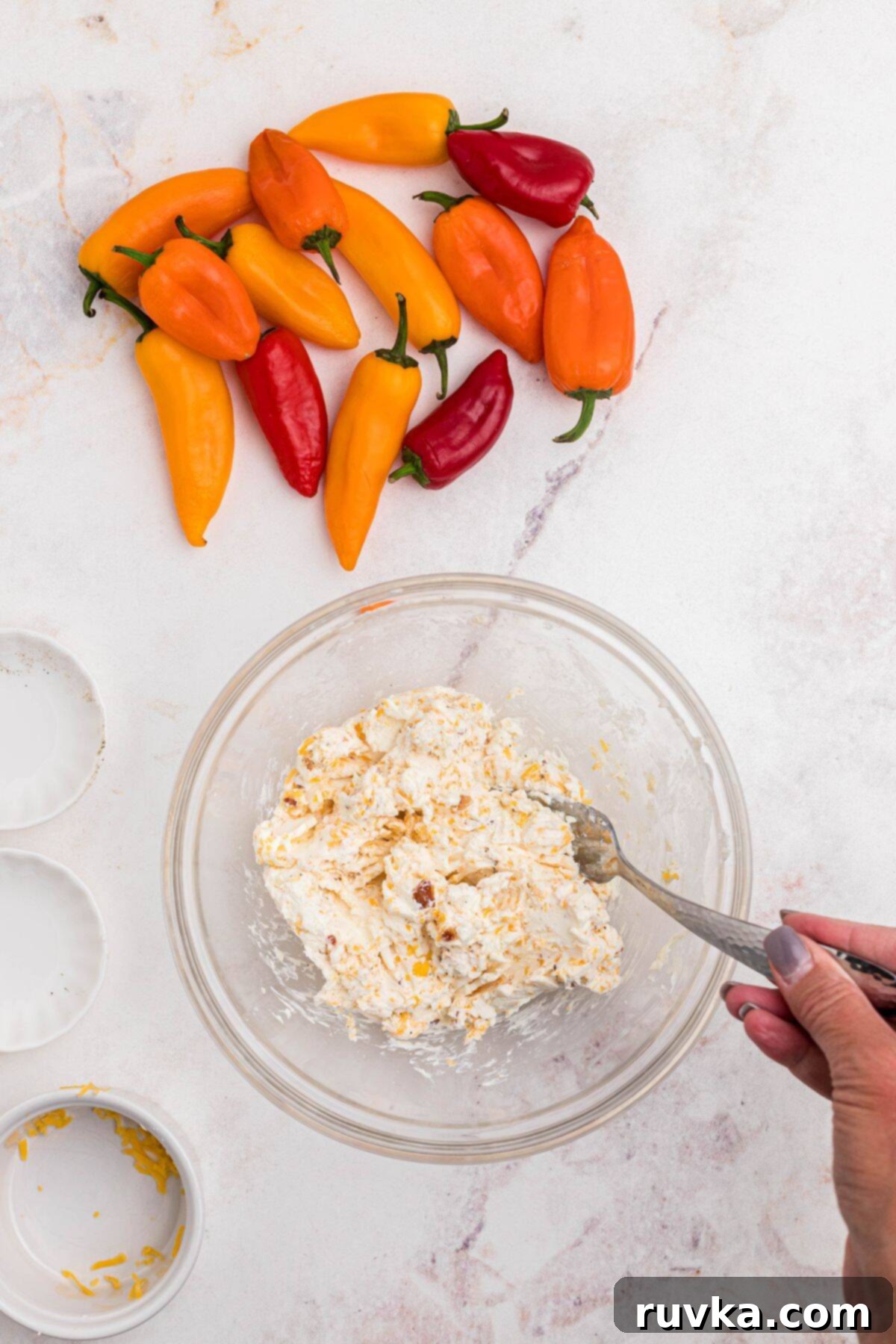 Crispy Air Fryer Stuffed Mini Peppers 4 Cream cheese, shredded cheddar, crumbled bacon, and garlic powder being mixed in a large bowl to create the savory filling.