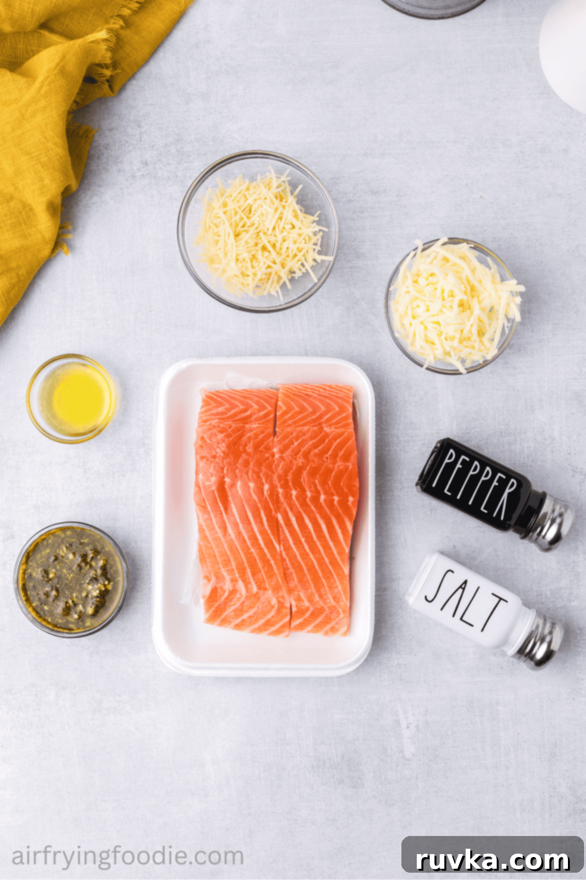 Crispy Air-Fried Pesto Parmesan Salmon 3 Arrangement of fresh salmon fillets, pesto, olive oil, parmesan, mozzarella, salt, and pepper – all measured out for cheesy air fryer pesto salmon.
