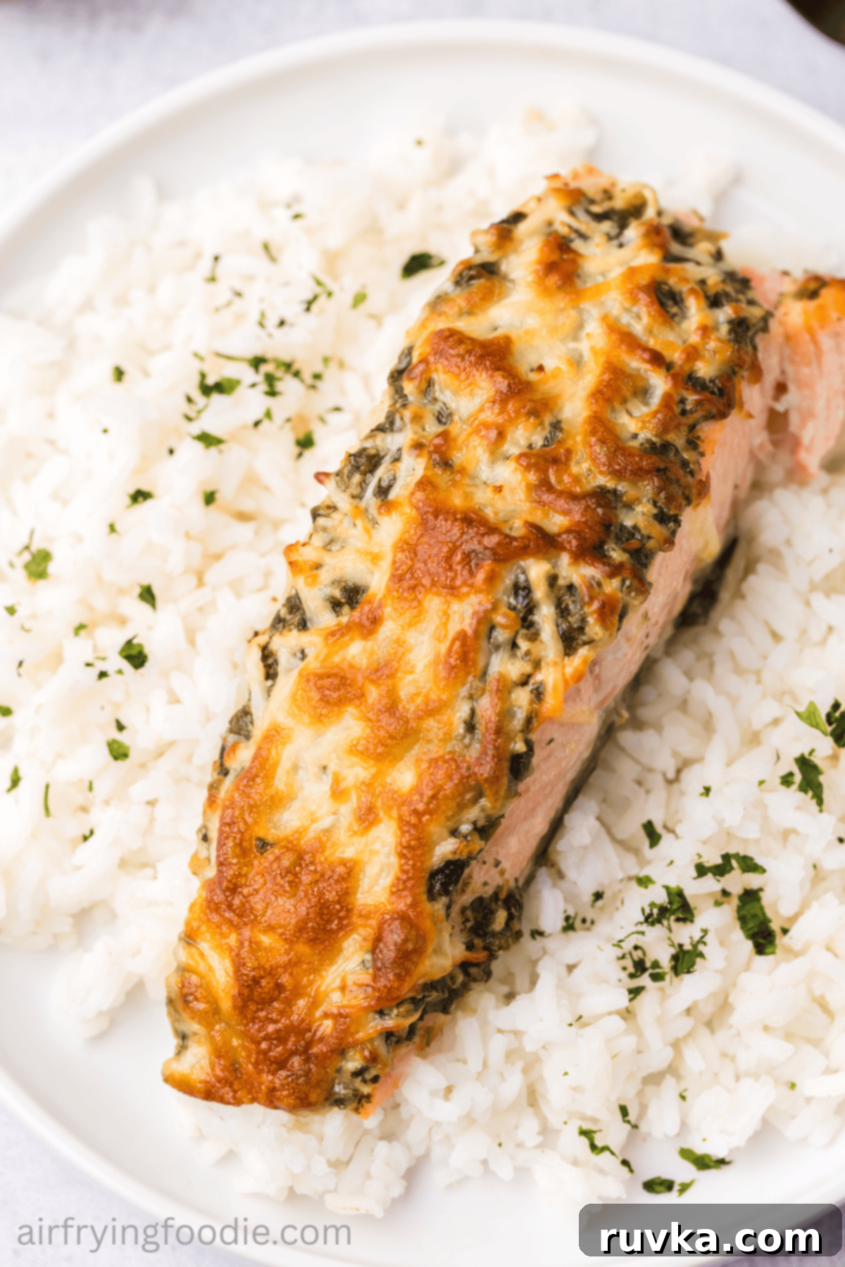 Crispy Air-Fried Pesto Parmesan Salmon 9 Close-up of a perfectly cooked cheesy pesto salmon fillet served on a bed of fluffy white rice.
