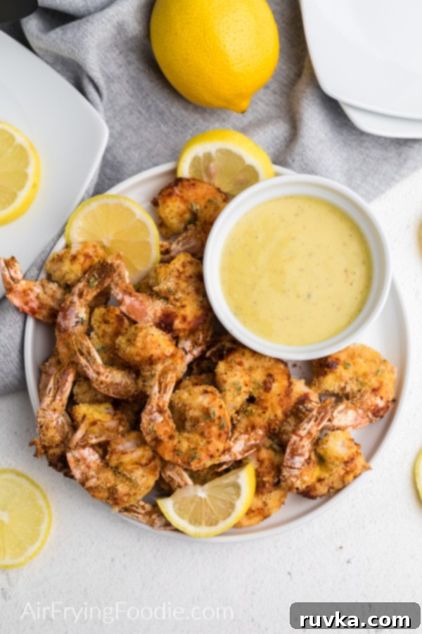 Crispy Keto Air Fryer Shrimp 3 Keto fried shrimp made in the air fryer on a white plate with lemon slices and dipping sauce - ready to serve.