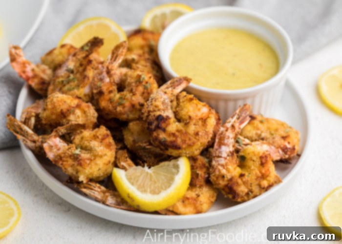 Crispy Keto Air Fryer Shrimp 5 Air Fryer keto Fried Shrimp on a white plate ready to eat - served with lemon slices and a dipping sauce.