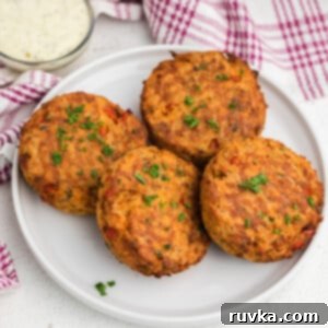 Crispy Air Fryer Salmon Cakes 10 Air Fryer Salmon Cakes on a white plate with dipping sauce on the side.
