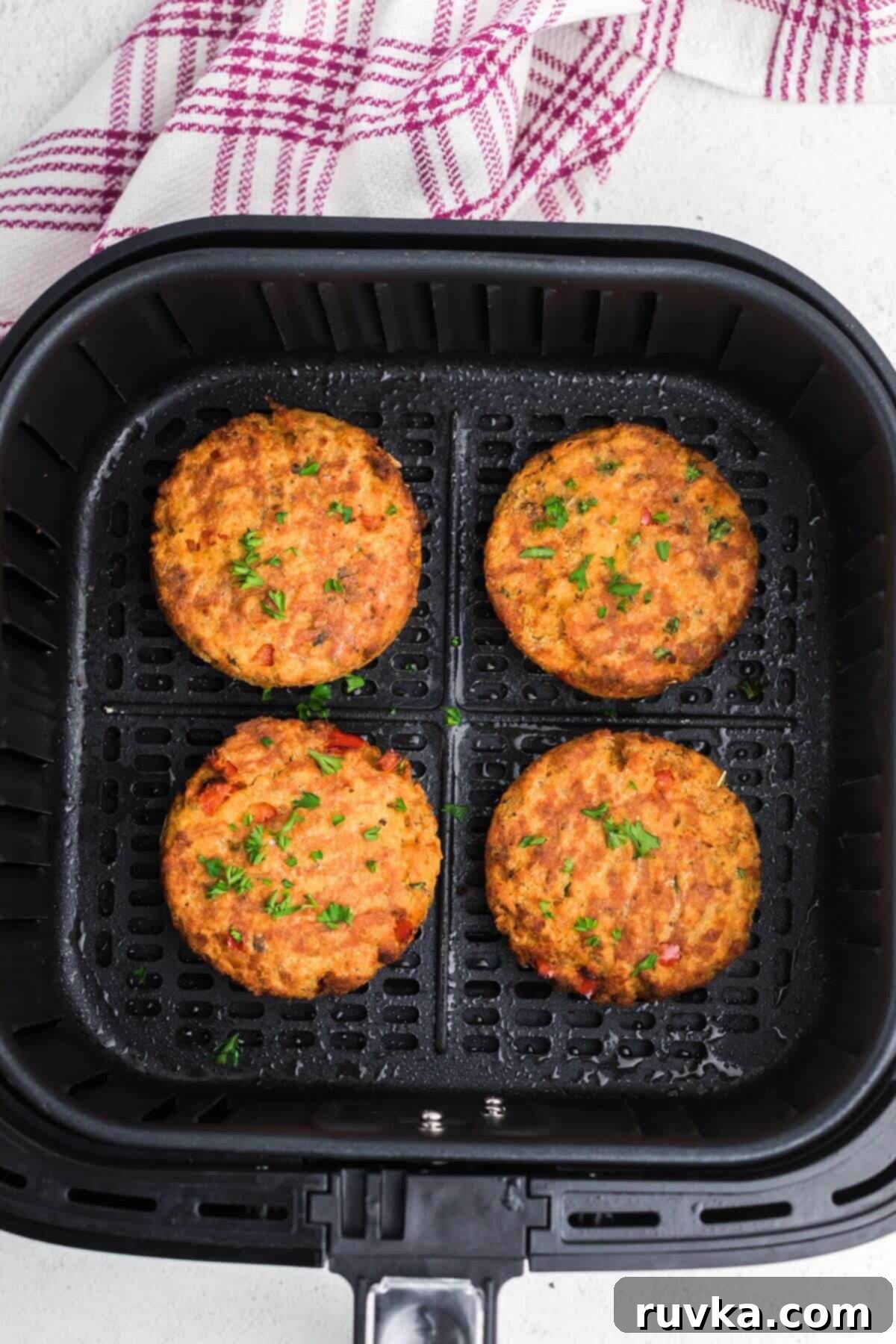 Crispy Air Fryer Salmon Cakes 7 Golden brown salmon patties in the air fryer basket after being cooked.
