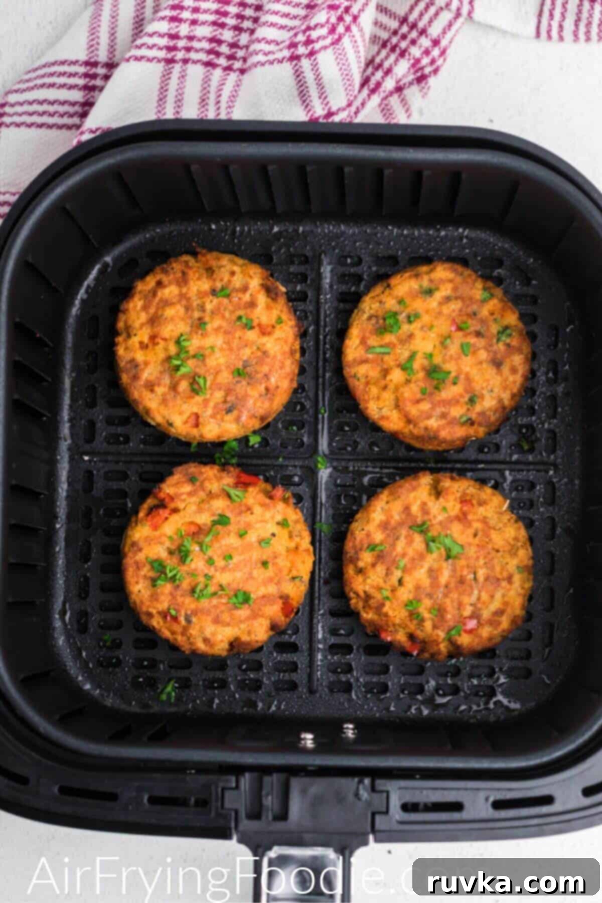 Crispy Air Fryer Salmon Cakes 8 Golden orange salmon cakes in the air fryer basket after being cooked.