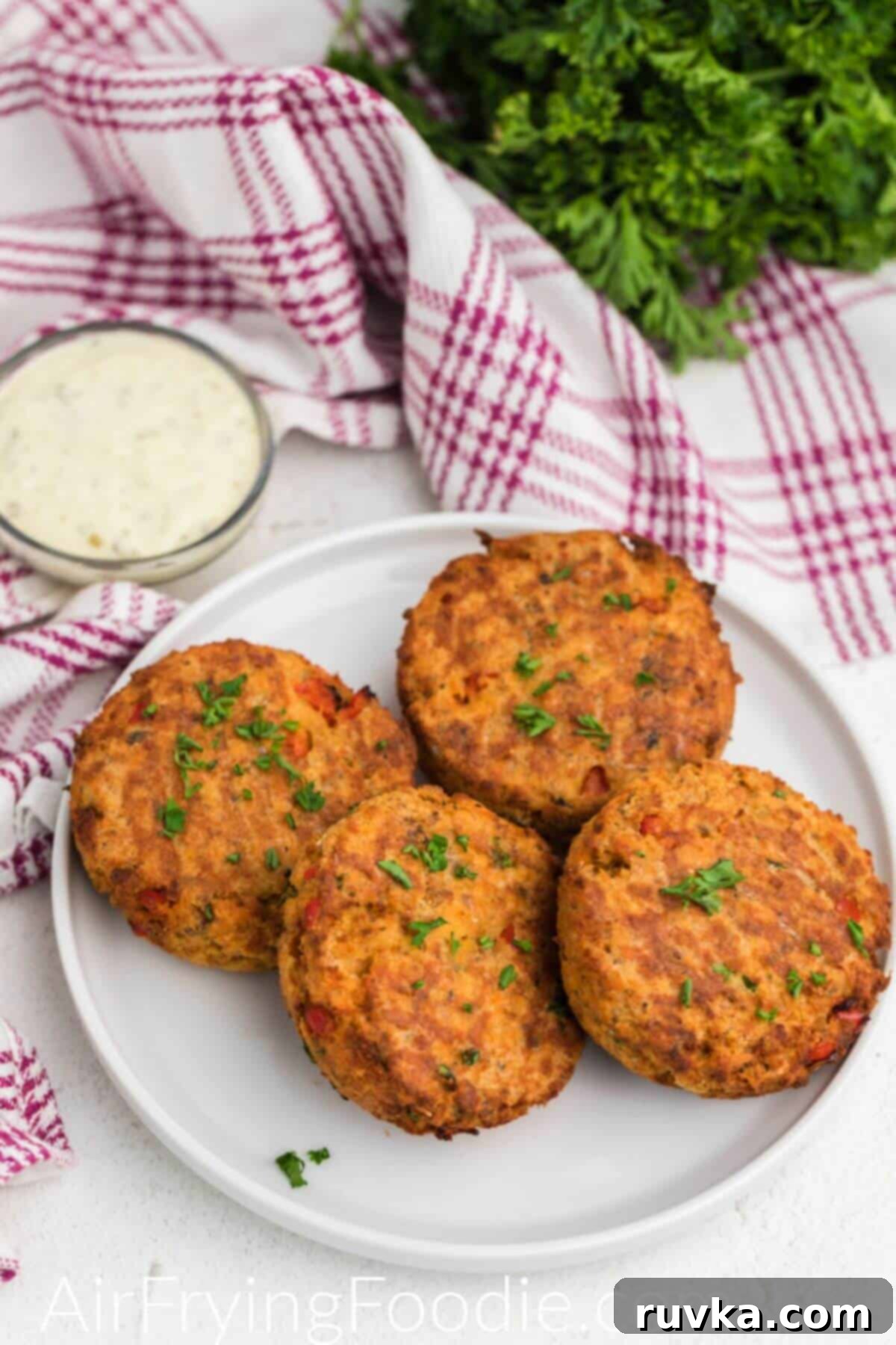 Crispy Air Fryer Salmon Cakes 9 Golden crispy salmon cakes stacked on a white plate.