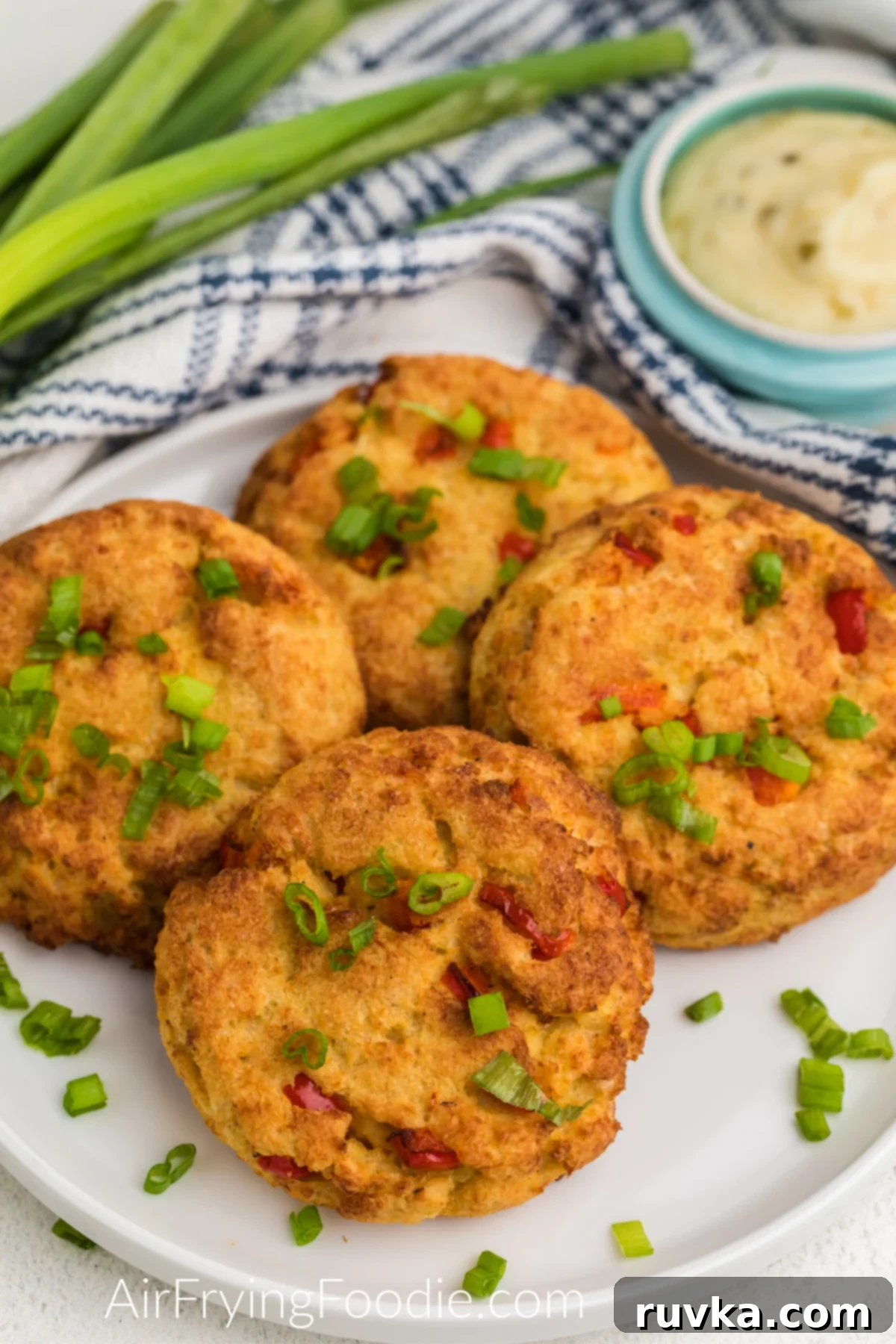 Crispy Air Fryer Crab Cakes 2 Cooked crab cakes made in the air fryer on a white plate ready to serve, garnished with fresh herbs.