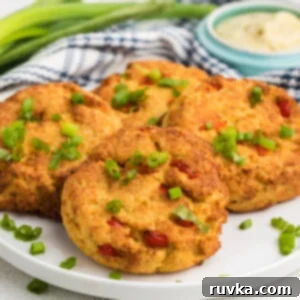 Crispy Air Fryer Crab Cakes 11 Air Fried Crab Cakes on a white plate garnished with green onion tops.