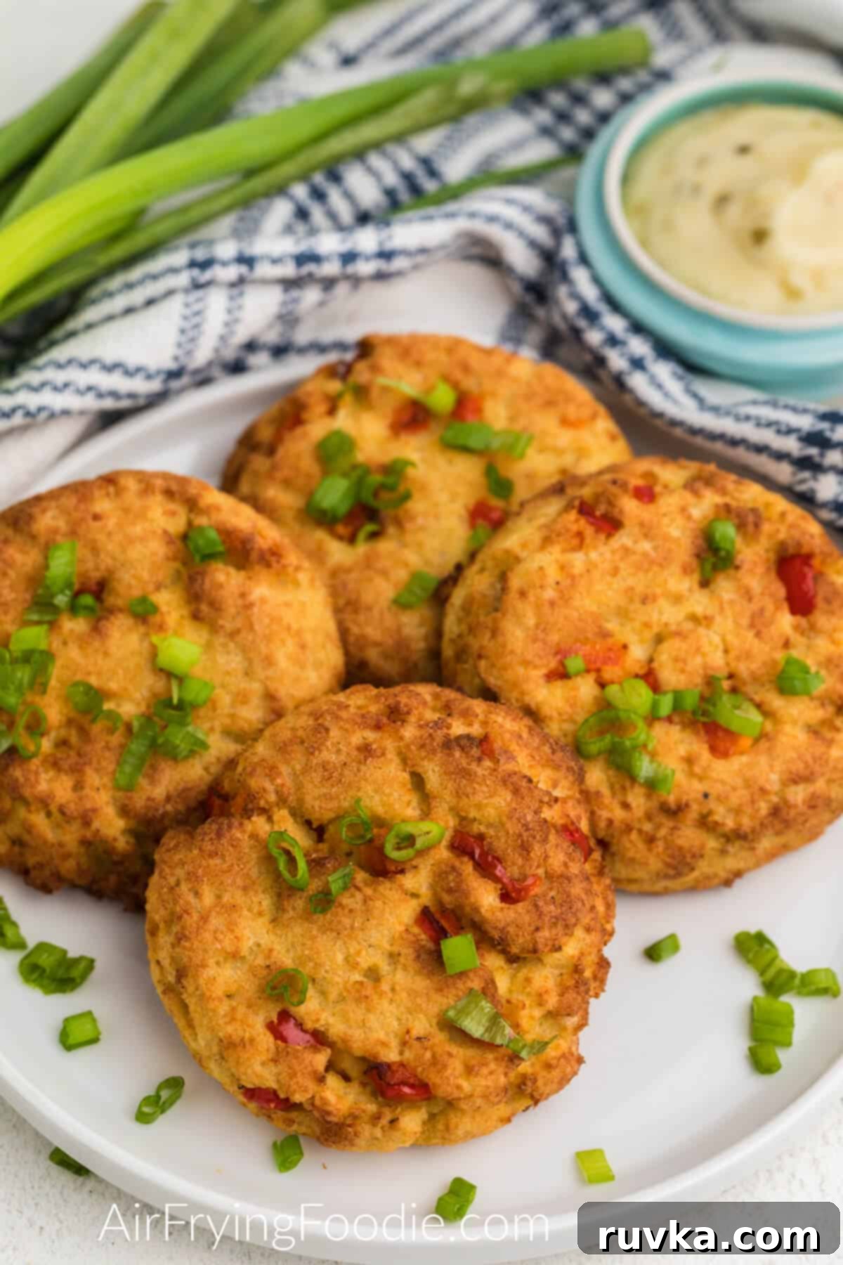 Crispy Air Fryer Crab Cakes 8 Air fried crab cakes on a plate, garnished with green onion tops, ready to serve.