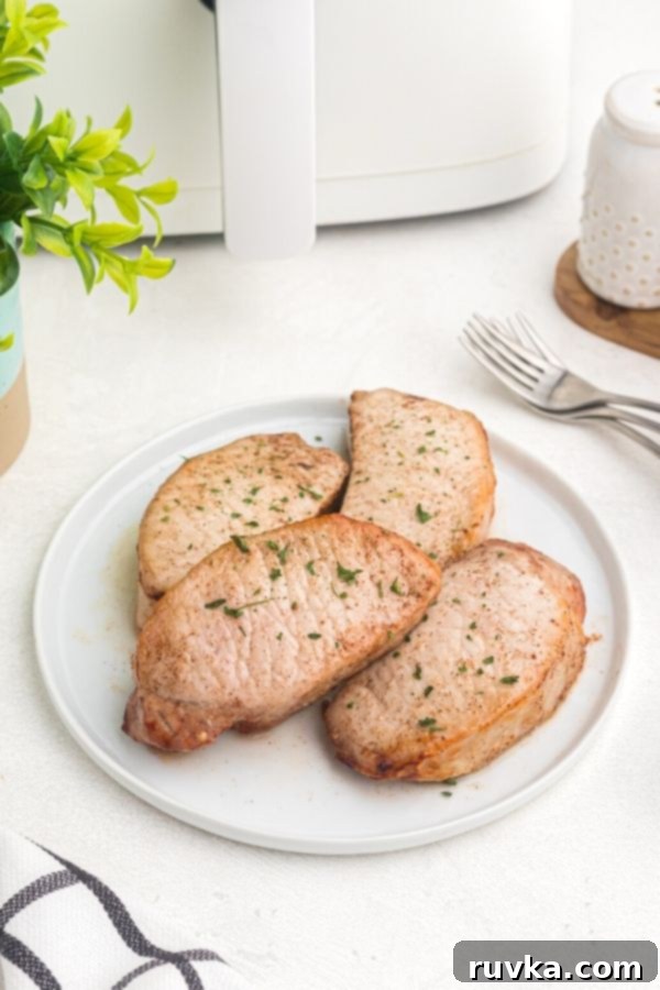 Juicy Air Fryer Maple Glazed Pork Chops 3 Glazed pork chops on a white plate garnished with parsley flakes