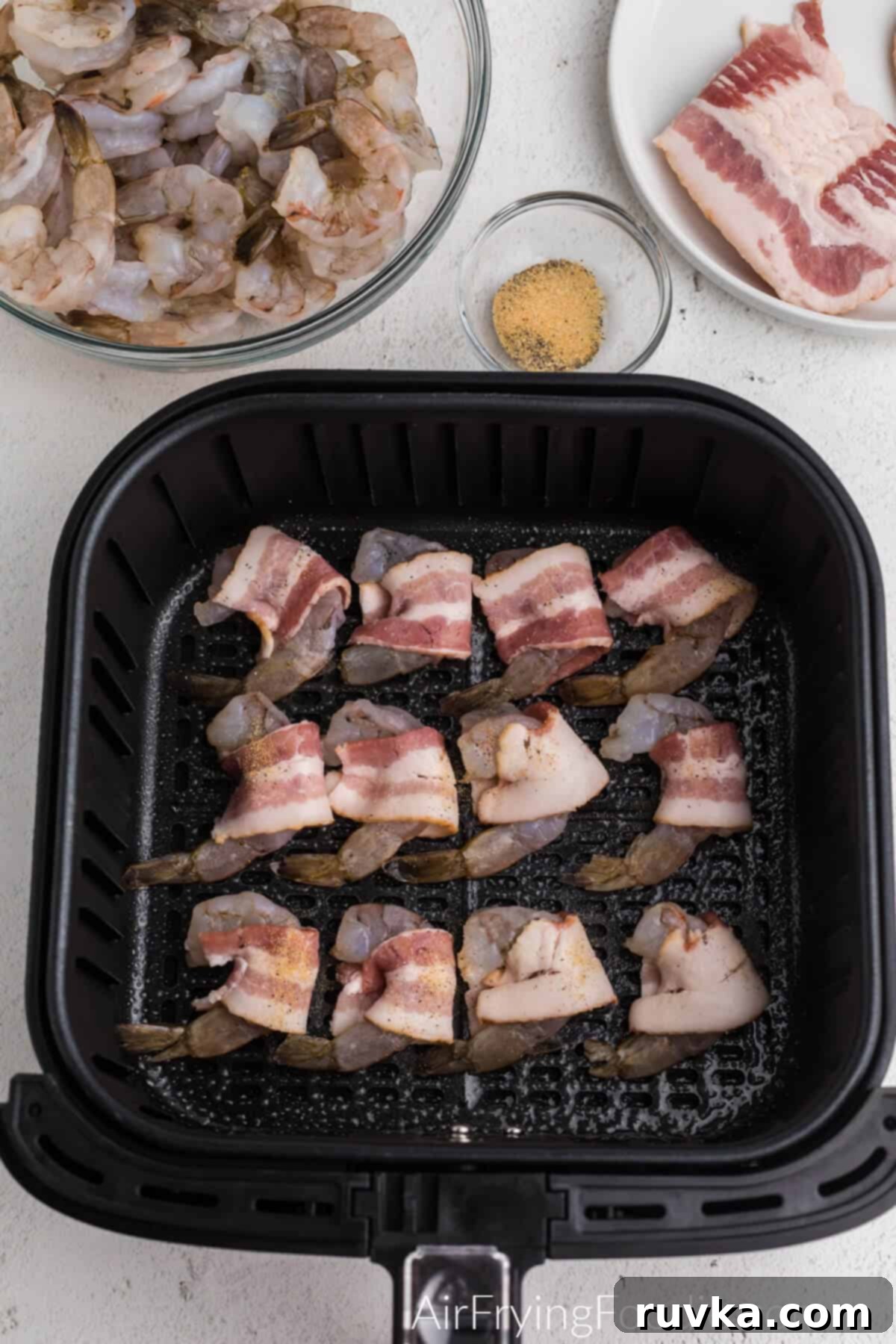 Crispy Air Fryer Bacon Wrapped Shrimp 4 Bacon wrapped shrimp arranged in a single layer in the air fryer basket, ready for cooking.