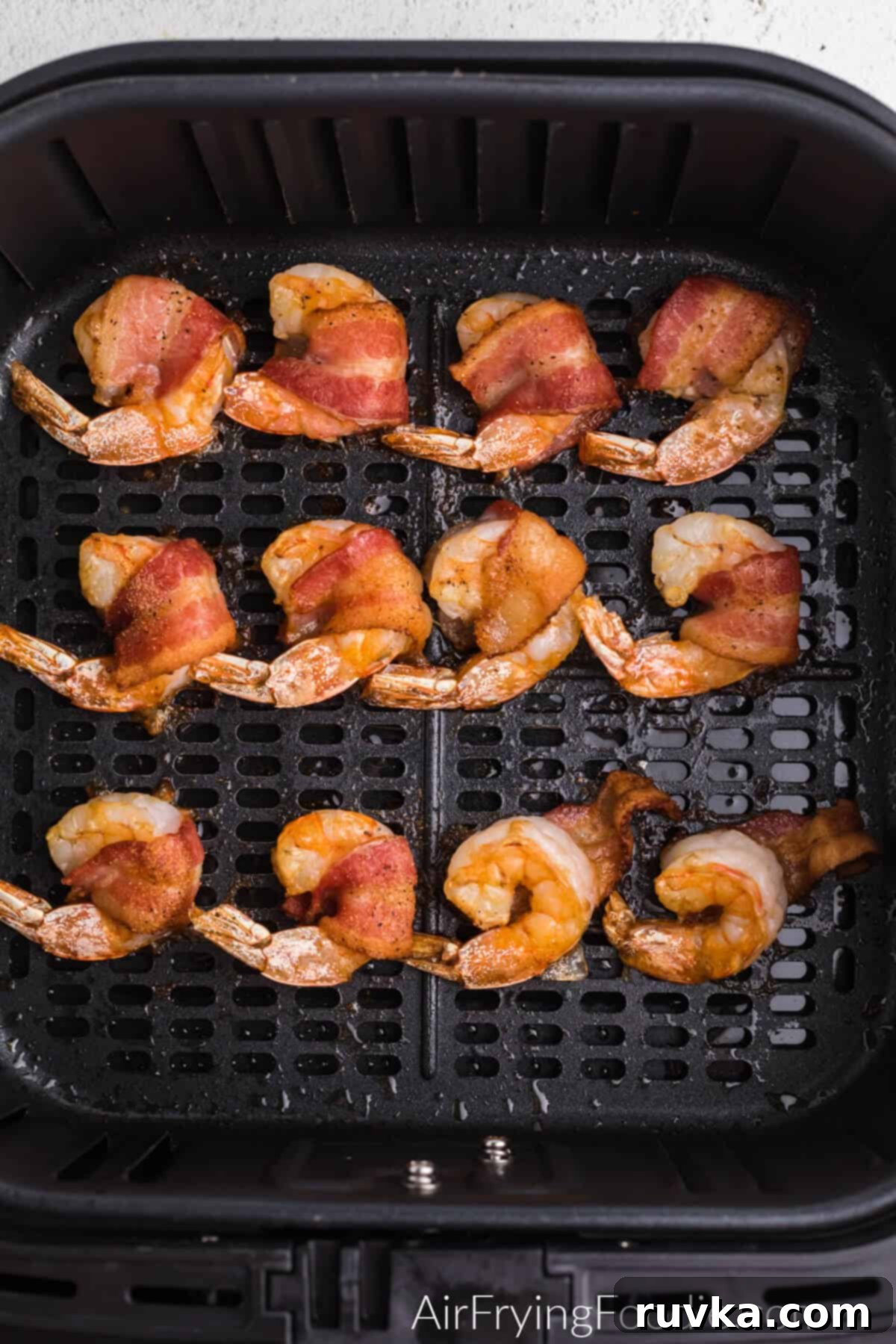 Crispy Air Fryer Bacon Wrapped Shrimp 5 Crispy bacon wrapped shrimp in the air fryer basket after cooking, golden brown and ready to serve.