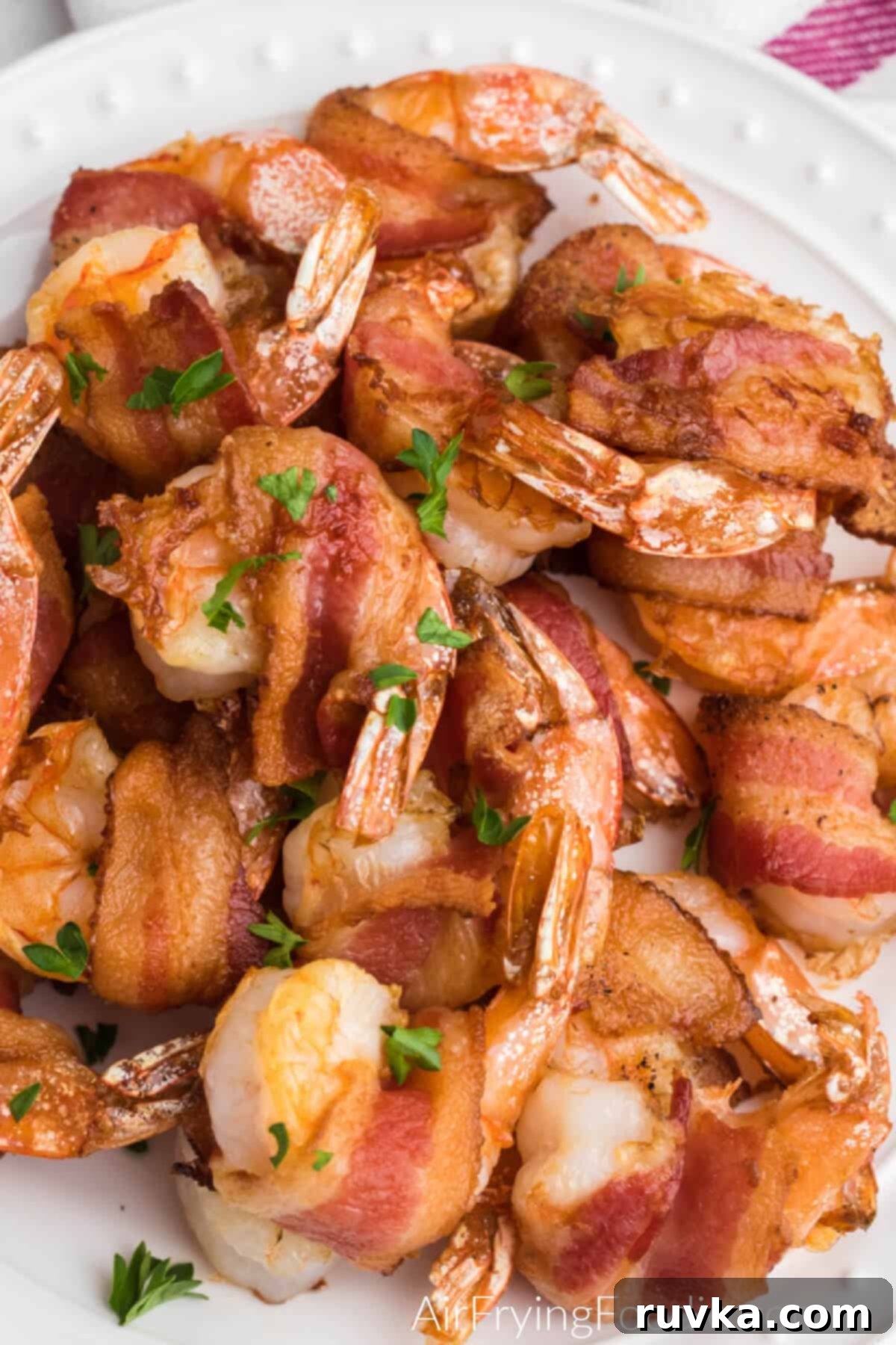 Crispy Air Fryer Bacon Wrapped Shrimp 7 Close up view of perfectly cooked air fryer bacon wrapped shrimp, garnished with fresh herbs and ready to eat.