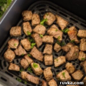 Easy Air Fryer Beef Recipes 3 Close-up of golden brown garlic steak bites in an air fryer basket.