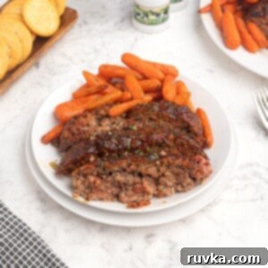 Easy Air Fryer Beef Recipes 9 Perfectly cooked and sliced meatloaf on a white plate, served with a side of tender baby carrots.