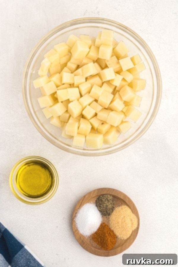 Crispy Air Fryer Breakfast Spuds 3 Ingredients needed for breakfast potatoes. Olive oil, seasonings, and cubed potatoes, uncooked.