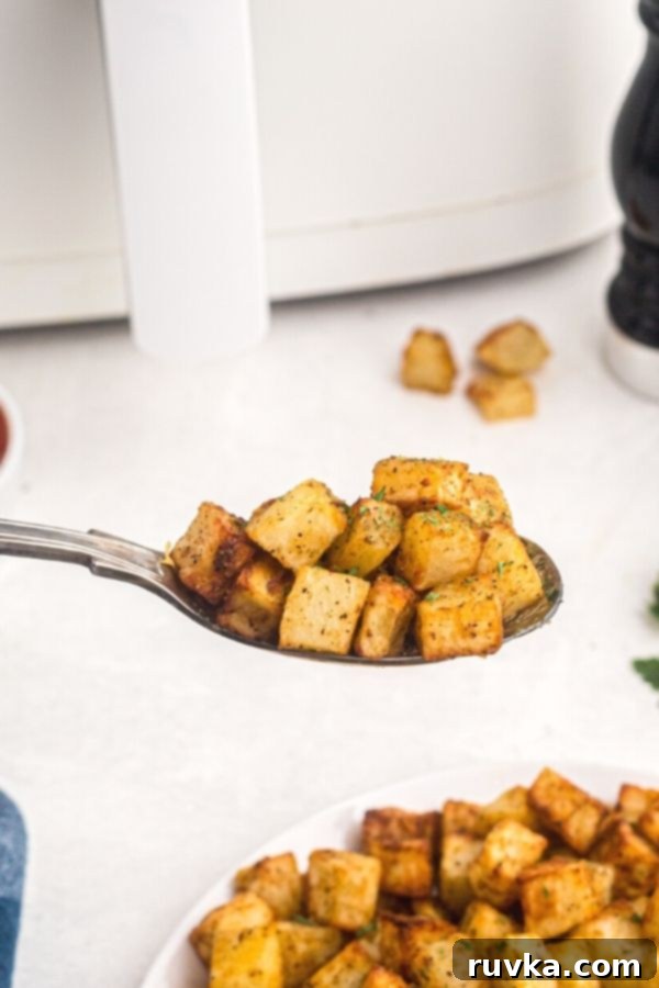 Crispy Air Fryer Breakfast Spuds 7 Spoonful of golden breakfast potatoes, cooked and garnished with parsley flakes.
