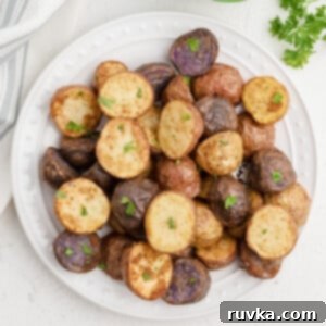 Crispy Air Fryer Roasted Potatoes 10 Air Fryer Roasted Potatoes in a white plate and garnished with fresh parsley. Ready to eat.