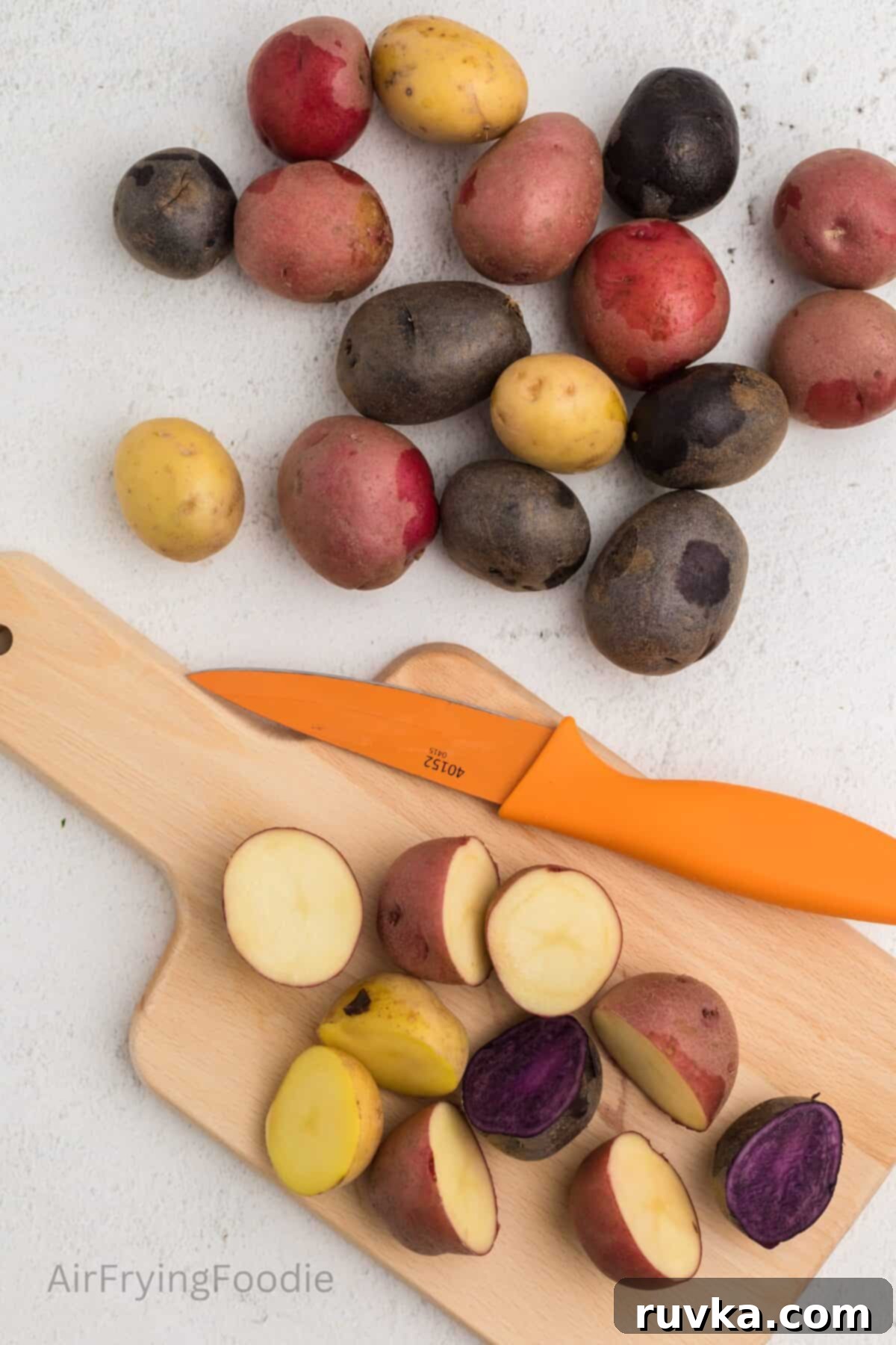 Crispy Air Fryer Roasted Potatoes 4 Washed and rinsed potatoes, with potatoes being cut in half on a cutting board.