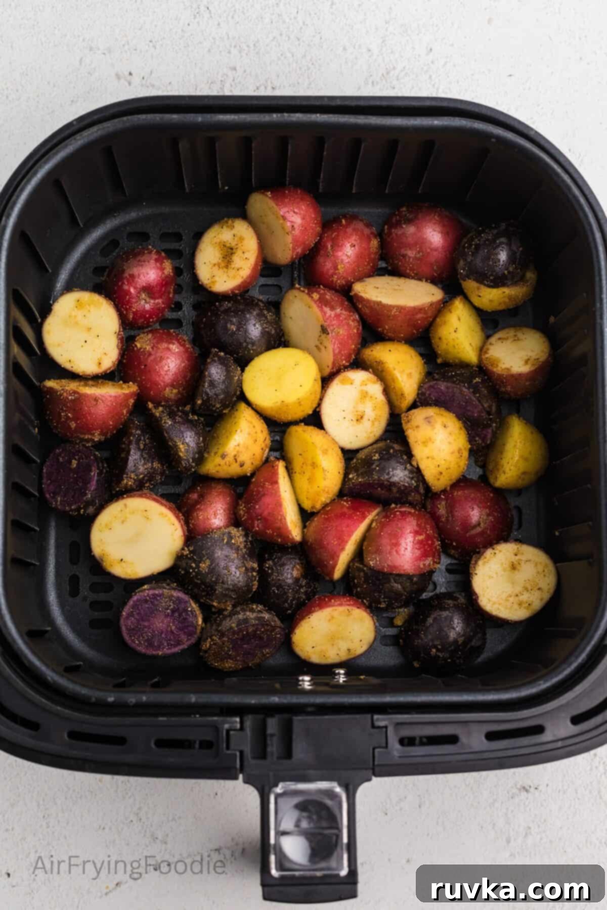 Crispy Air Fryer Roasted Potatoes 6 Seasoned potatoes in the basket of the air fryer, ready to be cooked.