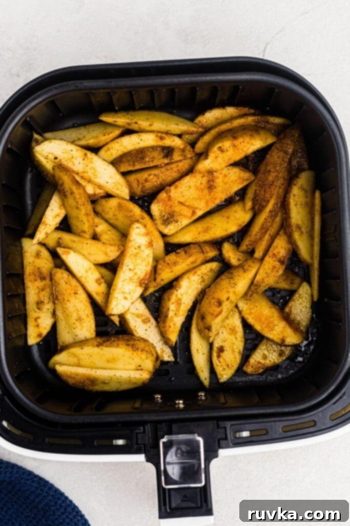 Crispy Air Fryer Potato Wedges 6 Uncooked potato wedges seasoned in an air fryer basket.