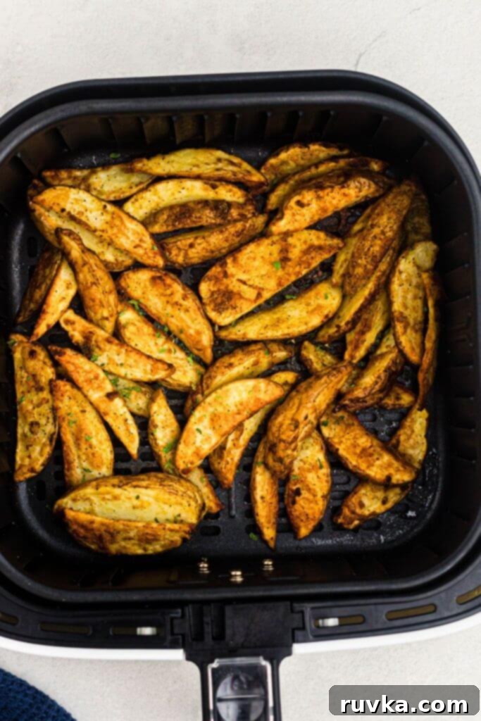 Crispy Air Fryer Potato Wedges 7 Seasoned potato wedges in the air fryer basket after being cooked until golden.