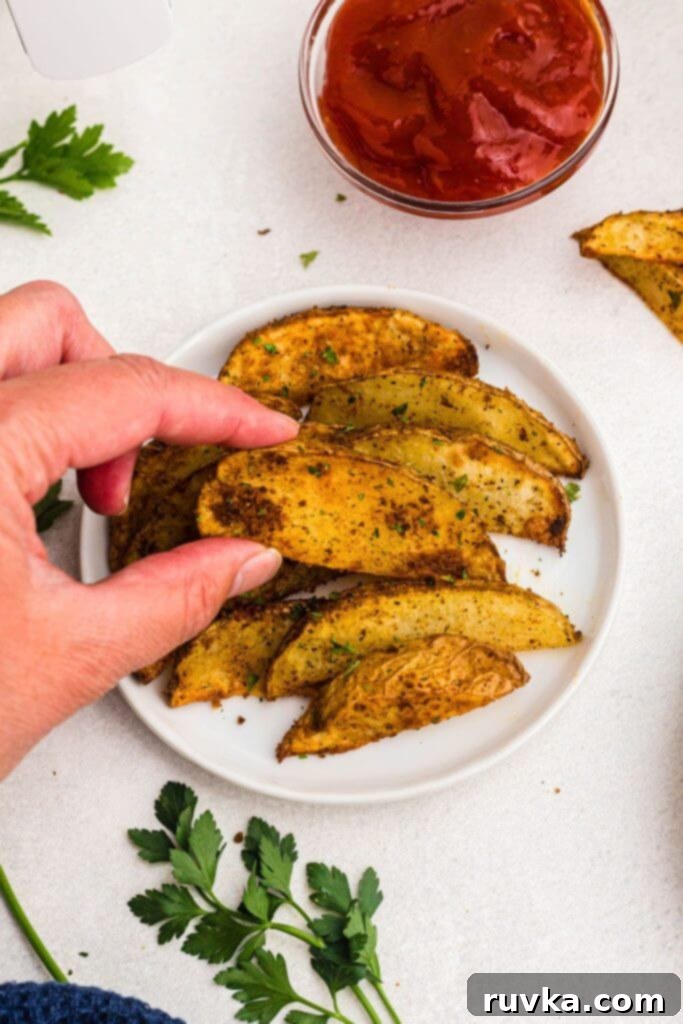 Crispy Air Fryer Potato Wedges 8 Golden seasoned potato wedges on a small white plate.