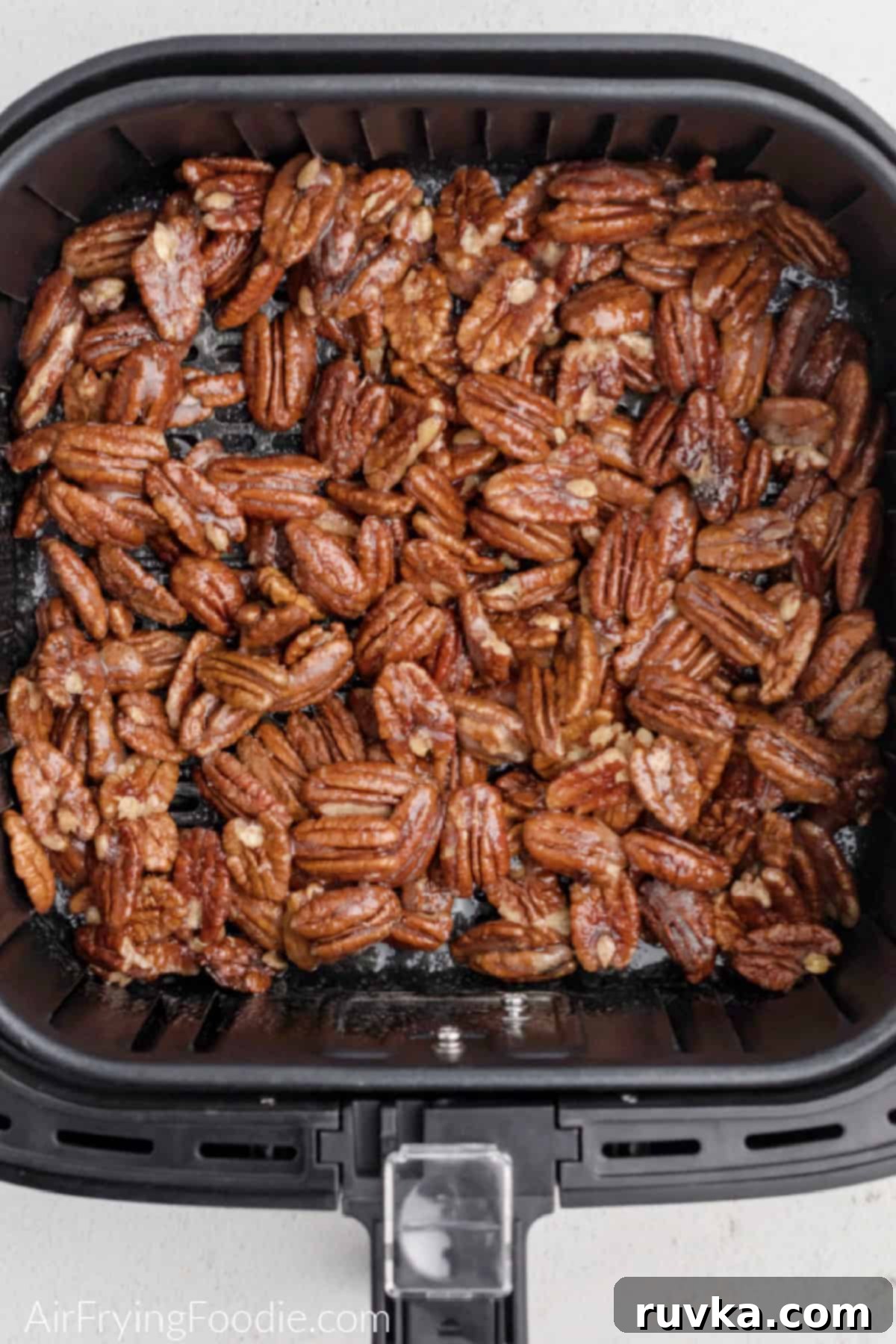 Golden Air Fryer Candied Pecans 7 Coated candied pecans spread in a single layer in the air fryer basket, ready for cooking.