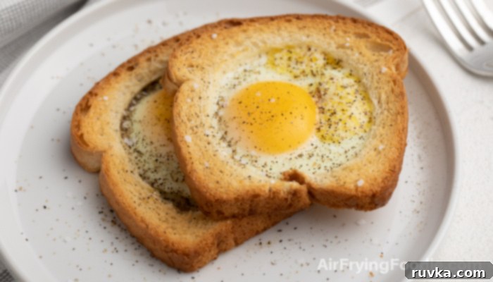 Crispy Air Fryer Egg Toast Baskets 3 Eggs in a basket topped with salt and pepper on a white plate.