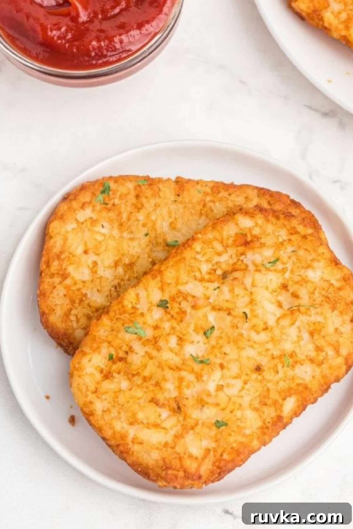Golden Crispy Air Fryer Hash Browns 2 Two golden brown and crispy hash brown patties cooked in an air fryer, served on a white plate, ready to be enjoyed as a perfect breakfast side.