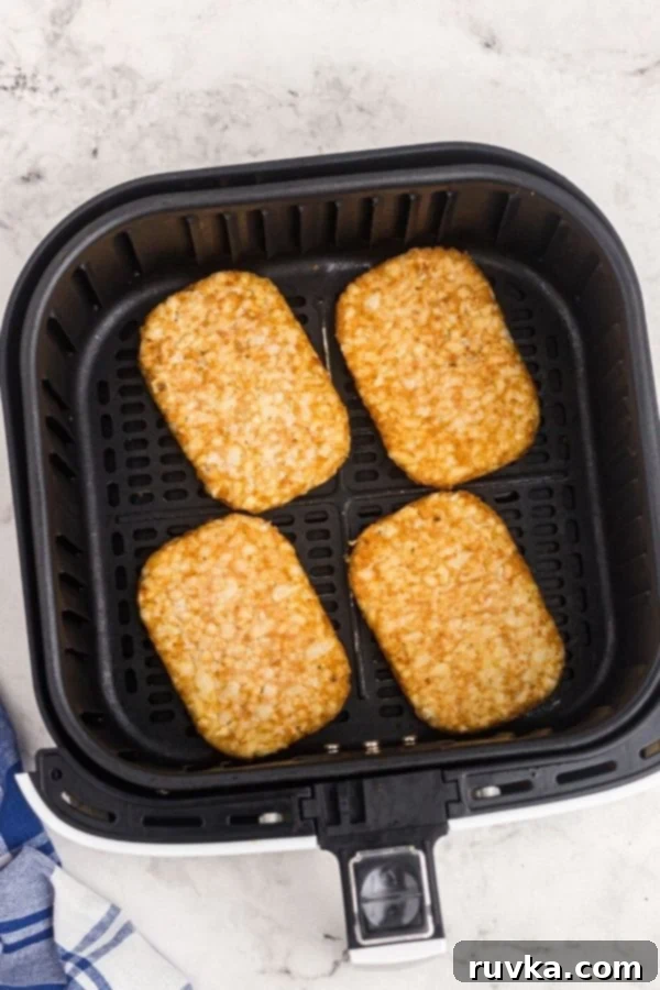Golden Crispy Air Fryer Hash Browns 4 Frozen hash brown patties neatly arranged in a single layer within the air fryer basket, ready for cooking to achieve optimal crispiness.