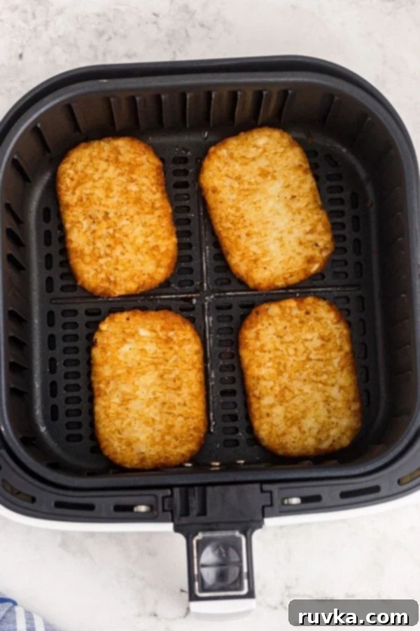 Golden Crispy Air Fryer Hash Browns 5 Crispy, golden brown hash brown patties cooking evenly in the air fryer basket, showing the perfect texture achieved during the air frying process.