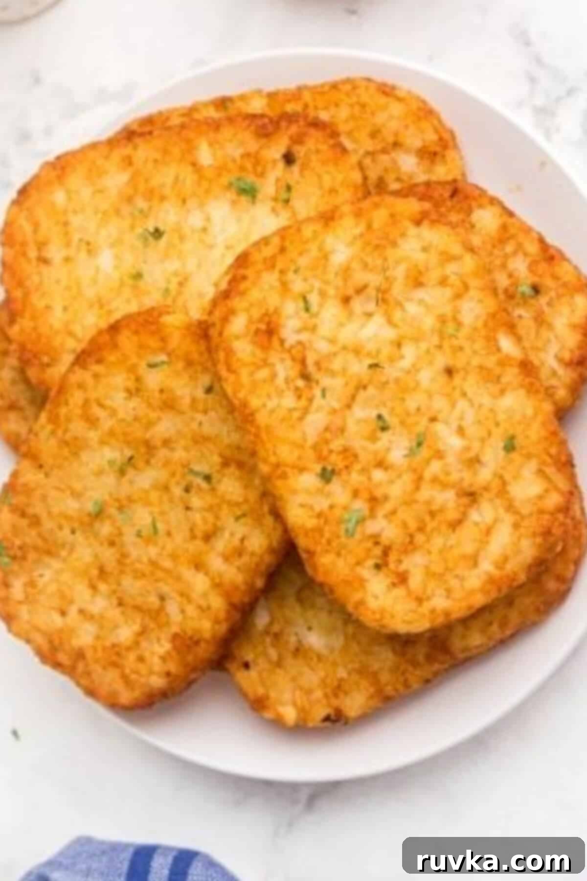 Golden Crispy Air Fryer Hash Browns 7 Perfectly golden hash brown patties, cooked to crispy perfection, arranged on a small white plate, garnished and ready for a delicious breakfast.