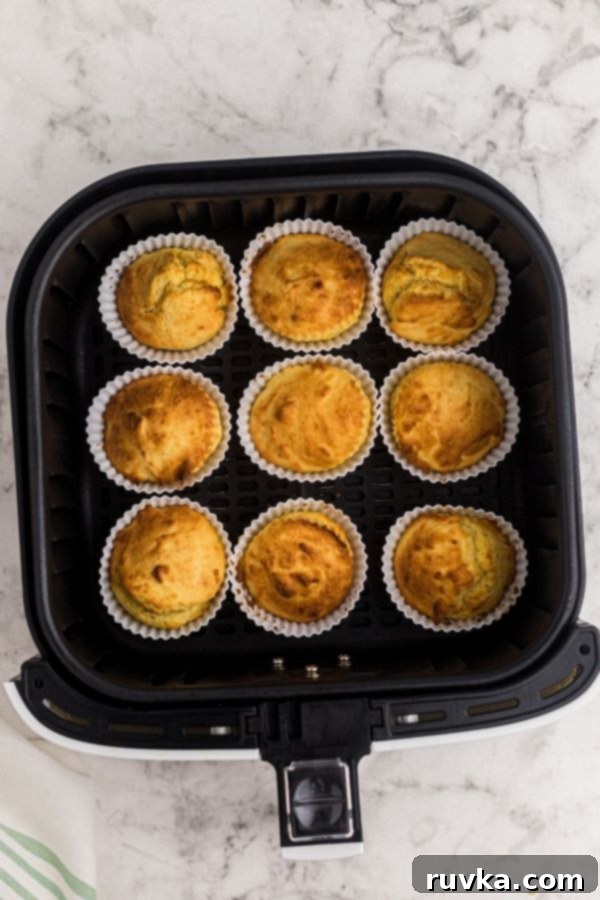 Air Fryer Cornbread Perfection 7 Silicone cups in the air fryer basket after being cooked until golden brown.
