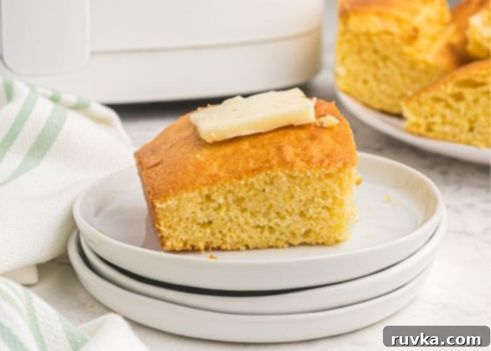 Air Fryer Cornbread Perfection 8 Close up photo of cornbread slice on a white plate with a fork.