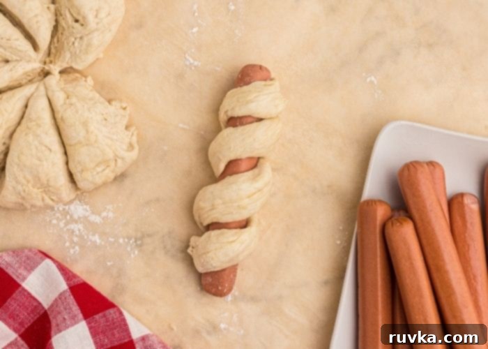 Crispy Air Fryer Pretzel Dogs 5 Close up photo of hot dog wrapped in pretzel dough, before cooking.