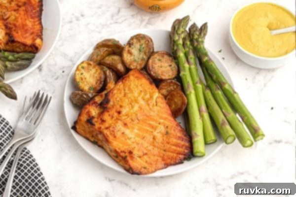 Effortless Air Fryer Honey Mustard Salmon 2 Crispy and golden salmon with a honey mustard glaze, served on a white plate with vibrant green asparagus and fluffy potatoes.