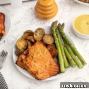 Effortless Air Fryer Honey Mustard Salmon 6 Cooked honey mustard glazed salmon served on a white plate with vibrant green asparagus.