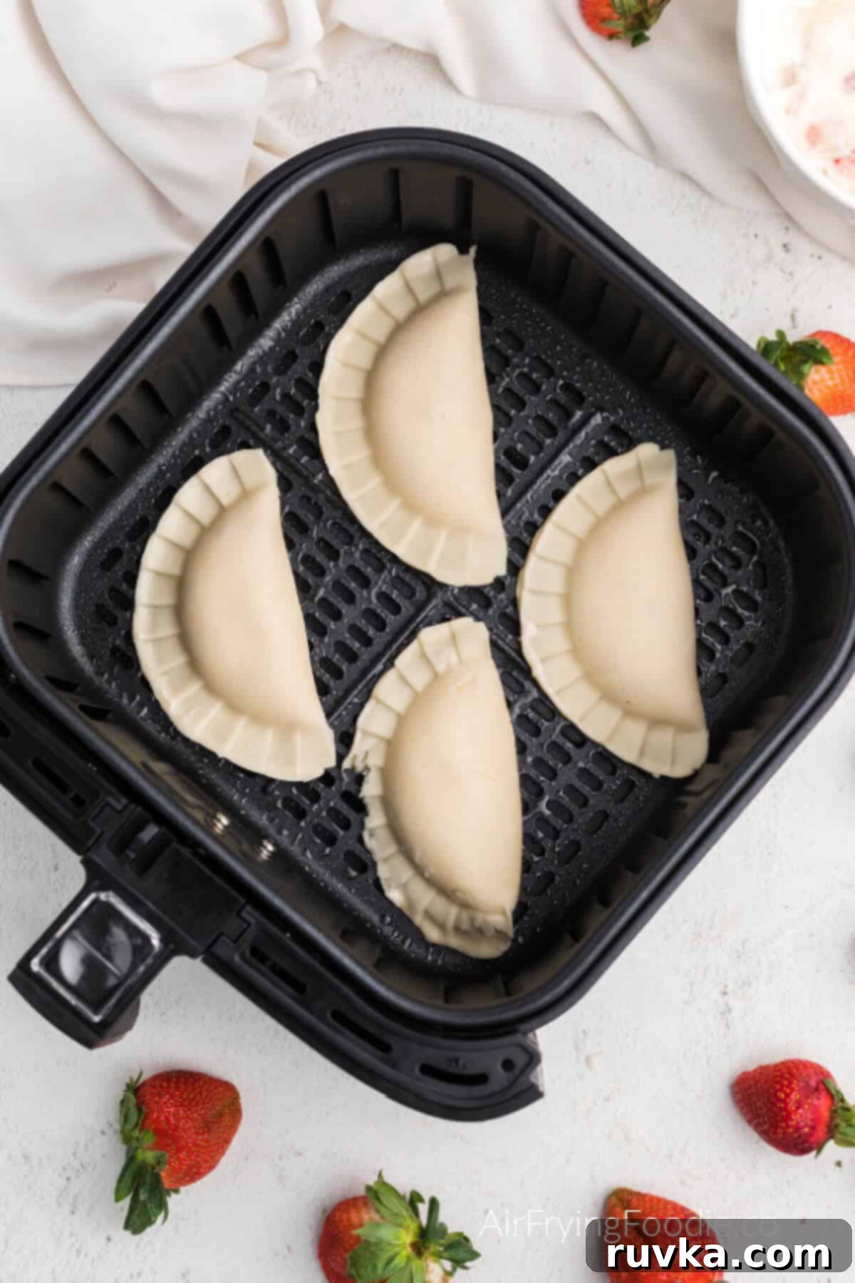 Easy Air Fryer Strawberry Cream Cheese Pie 5 Hand pies in air fryer basket, ready to cook.