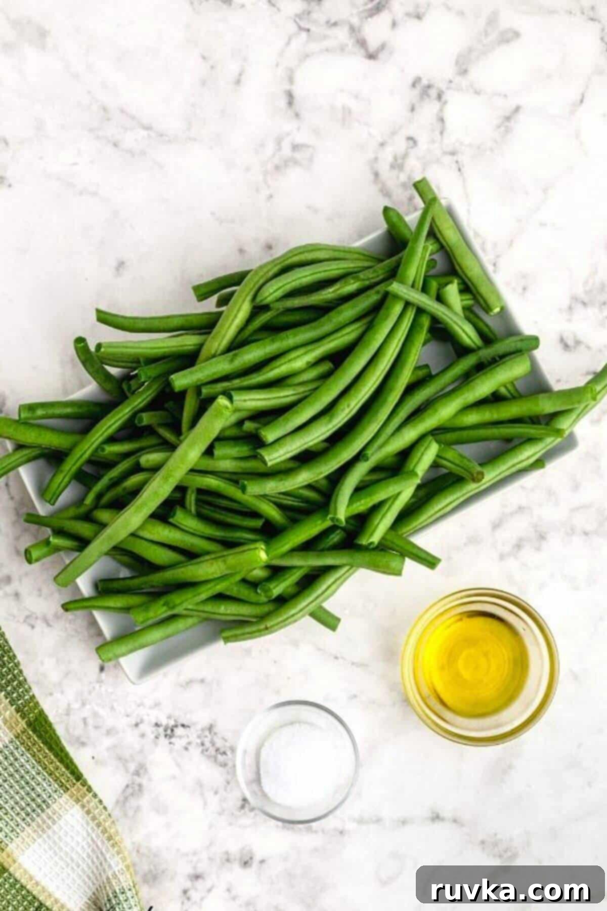 Crispy Air Fried Green Beans 3 Uncooked green beans, olive oil and seasonings measured on a white marble table.