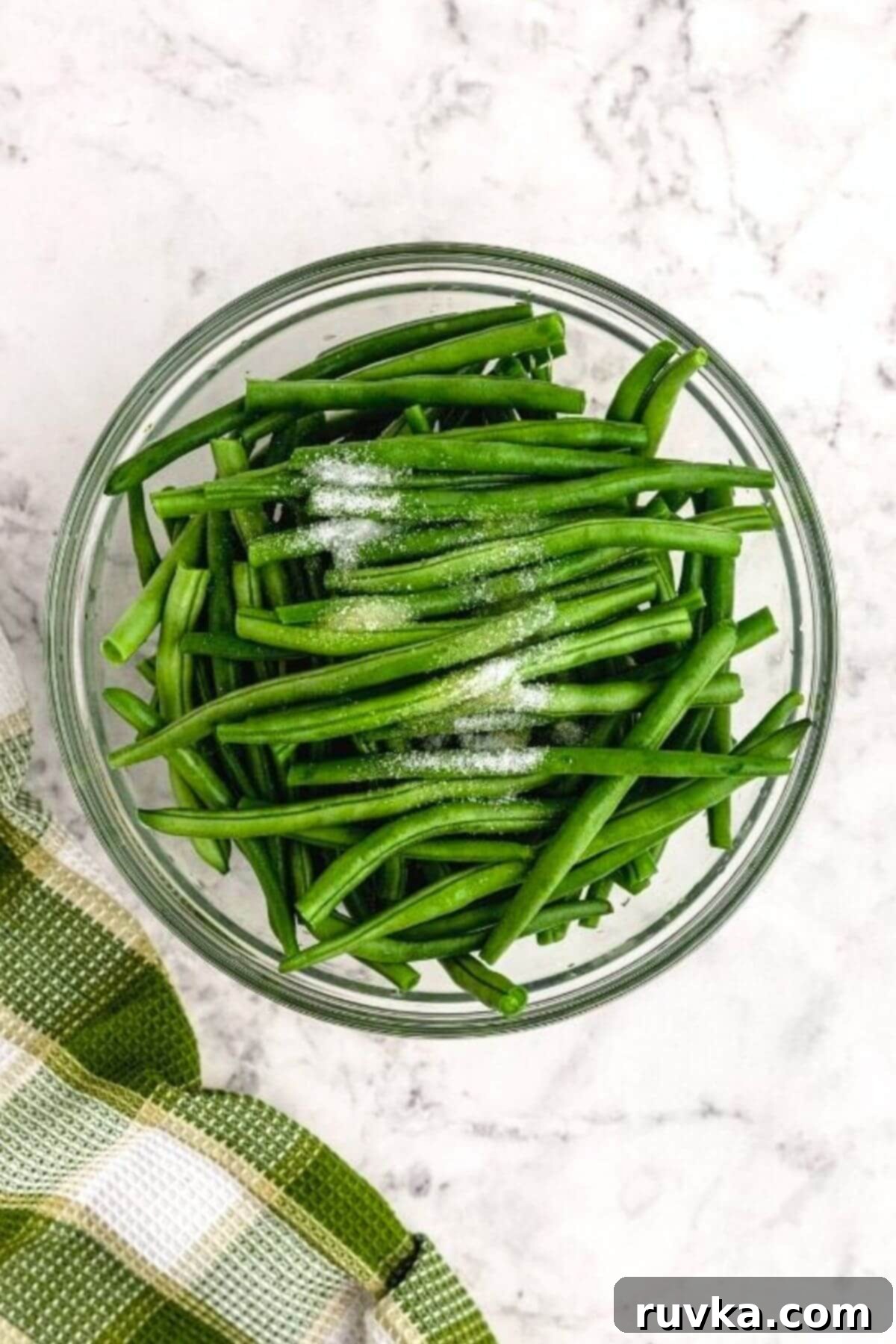 Crispy Air Fried Green Beans 4 Trimmed green beans in a clear bowl tossed with olive oil and seasonings.