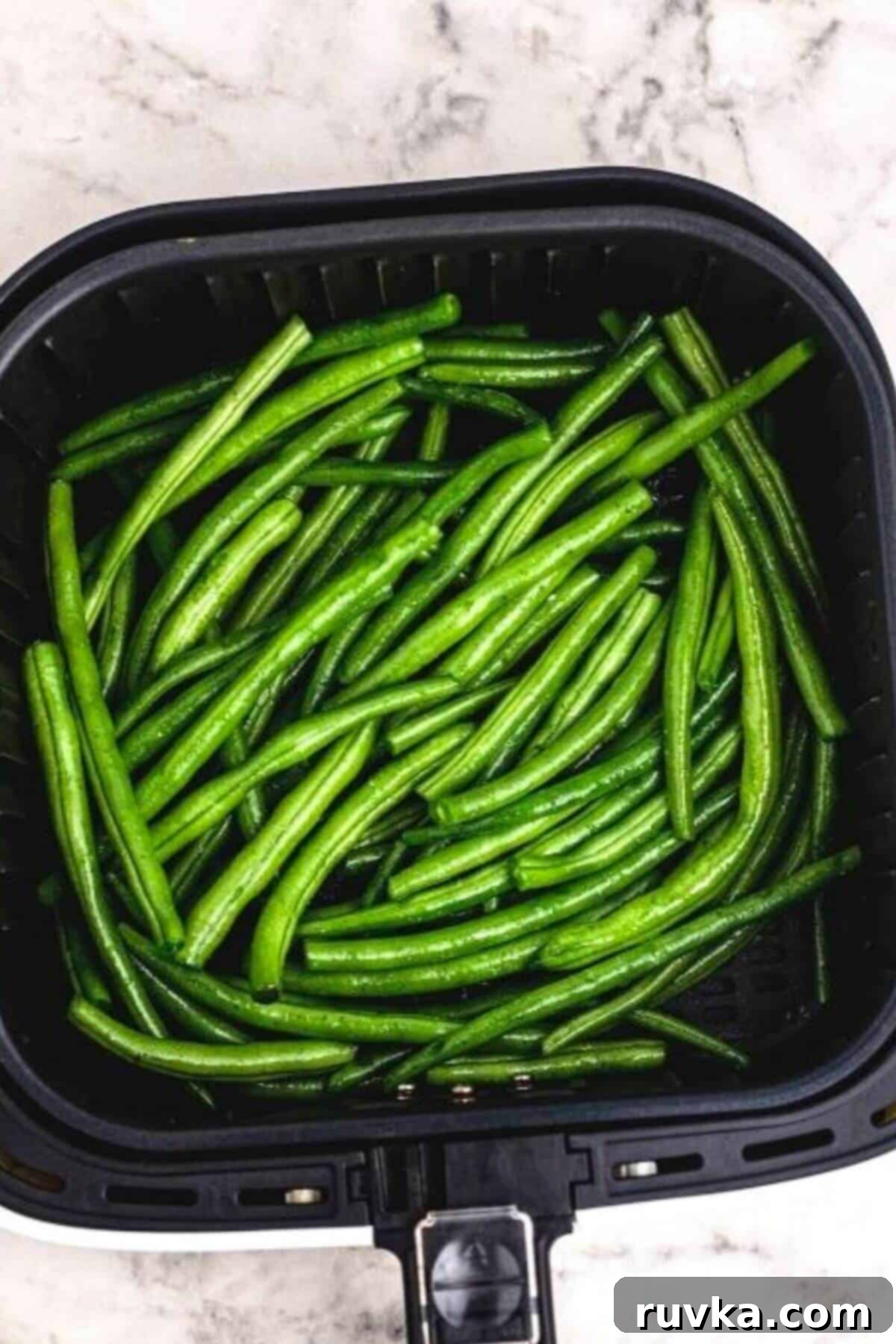 Crispy Air Fried Green Beans 5 Seasoned green beans in the air fryer basket before being cooked.