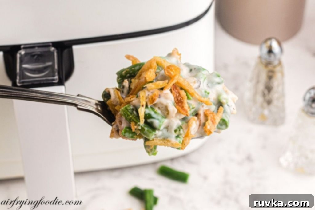 Crispy Air-Fried Green Bean Bake 8 Spoonful of green bean casserole being scooped out of dish in front of air fryer.