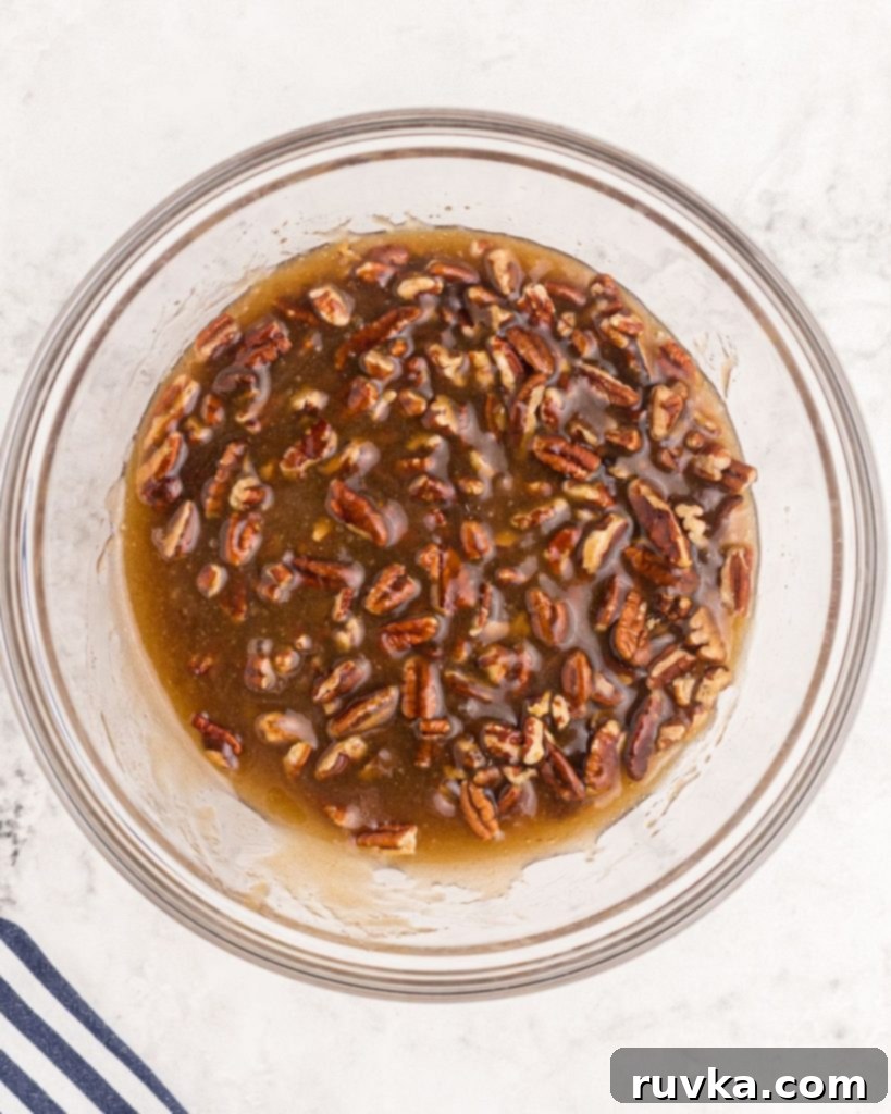 Perfect Air Fryer Pecan Pie 5 Rich pecan pie filling, after being thoroughly mixed, resting in a clear glass bowl, ready to be poured into the pie crust.